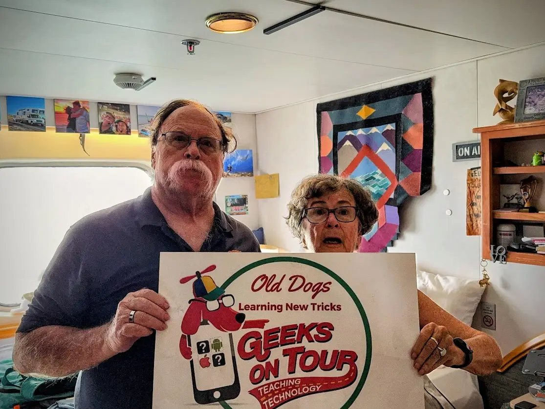 A couple taking a photo with a sign in their cabin in Villa Vie Odyssey.