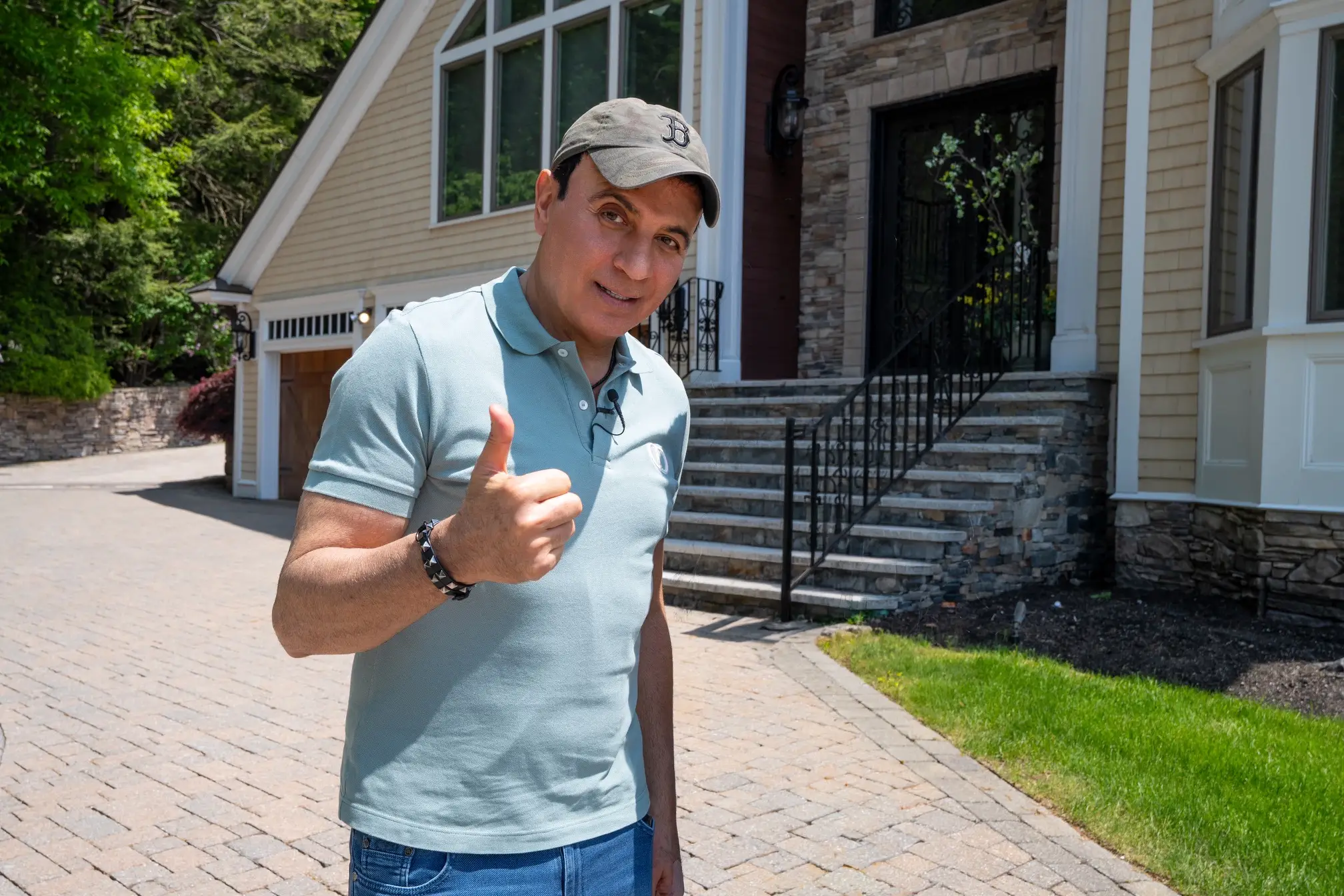 Charles Hanna poses in front of a house, making a thumbs-up sign