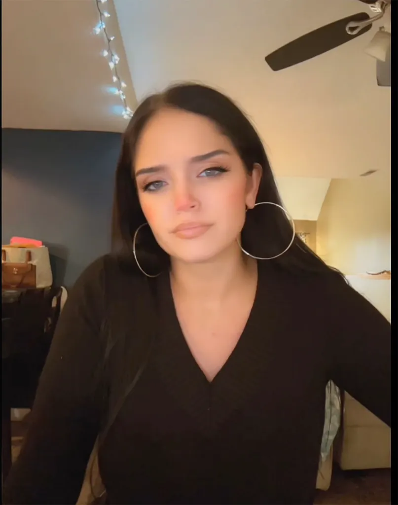 Gypsy Rose Blanchard wearing a black V-neck top and large hoop earrings indoors.