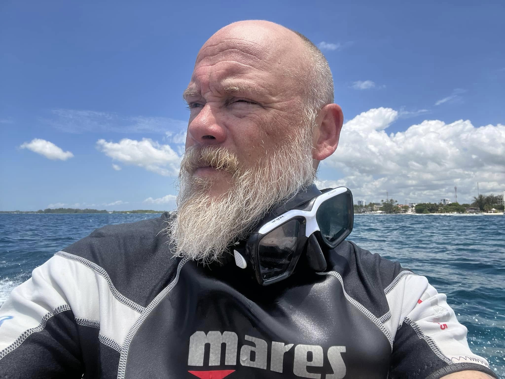 Bryan Seaver wearing a wetsuit and diving mask around his neck on a boat.