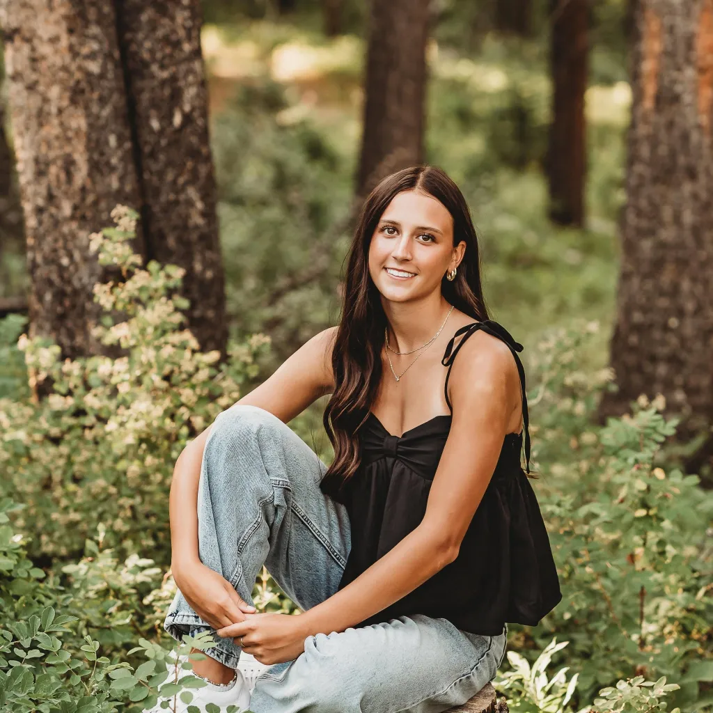 Kyann Dean sitting in a wooded area.