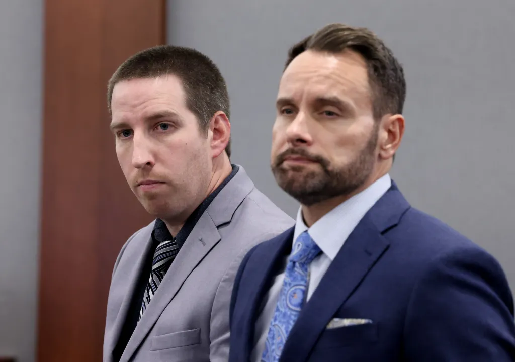 Two men in suits standing side-by-side in a courtroom.