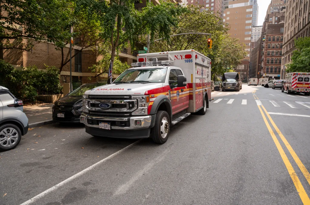 FDNY ambulance parked on a Manhattan street during the daytime, with city buildings and other cars in the background.