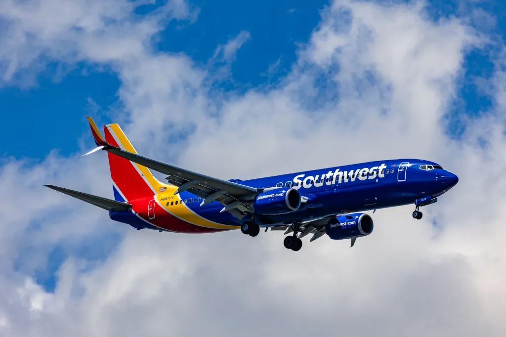 A Southwest Airlines Boeing 737 plane in flight against a cloudy blue sky.