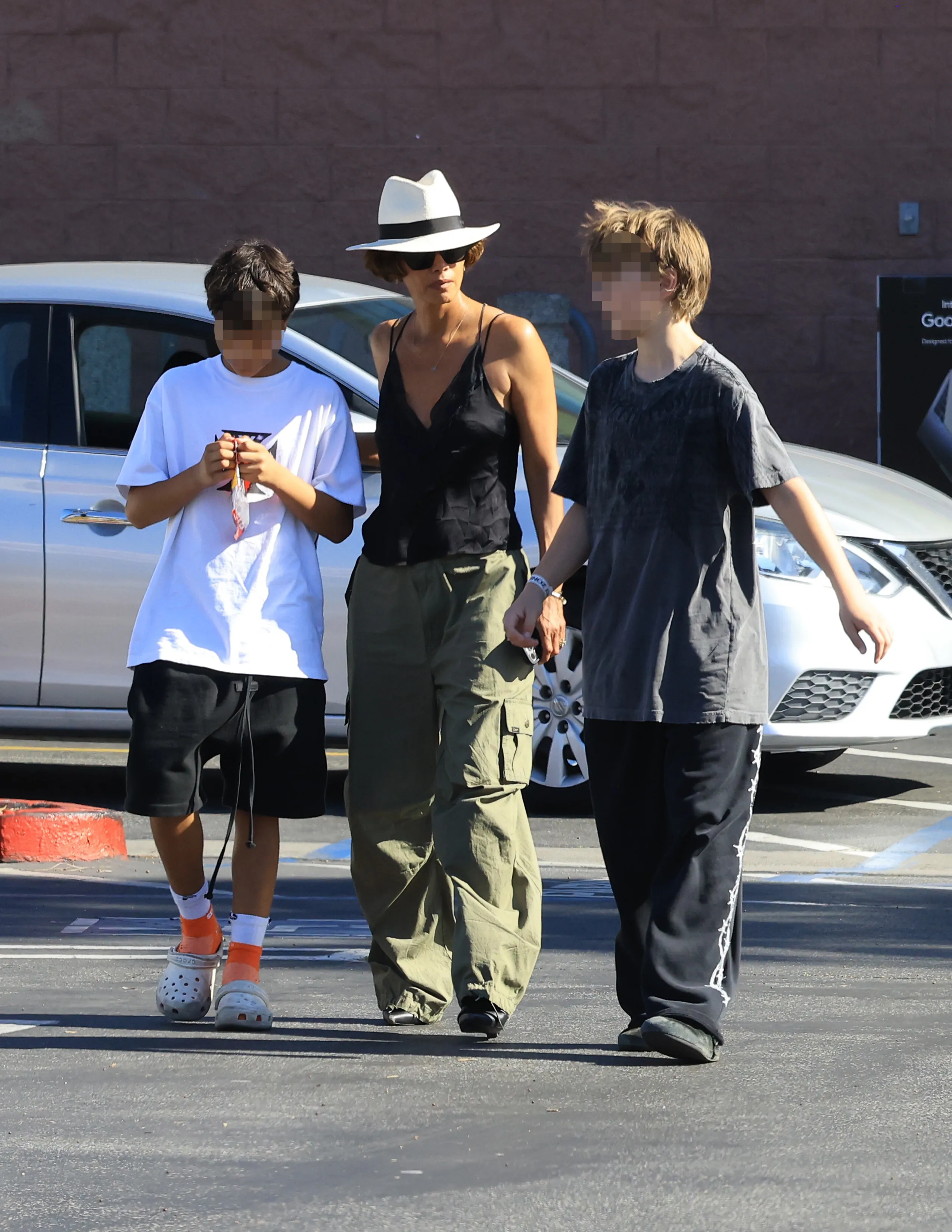 Halle Berry walks through a parking lot with two children.