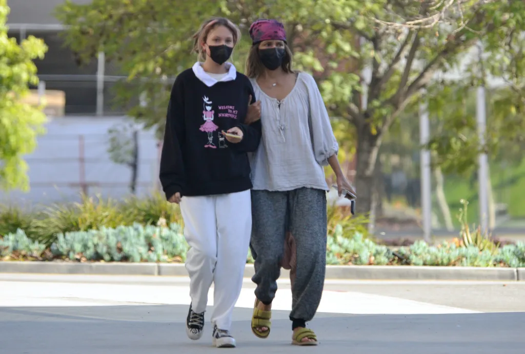 Halle Berry walking outdoors with her daughter, both wearing face masks.