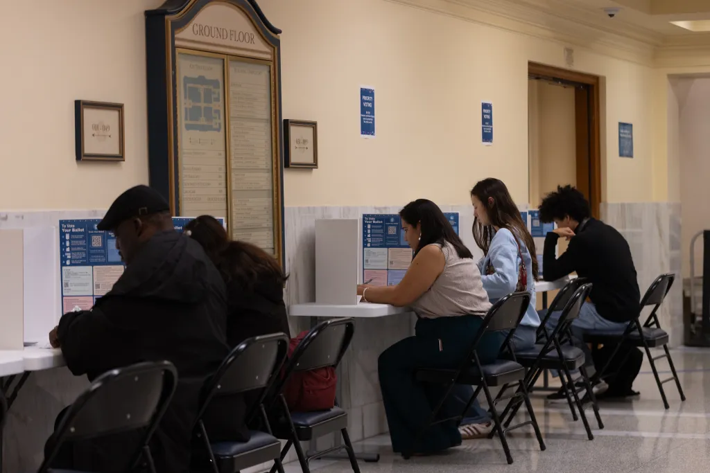 Voters fill out their ballots at carrels set up in a hallway.