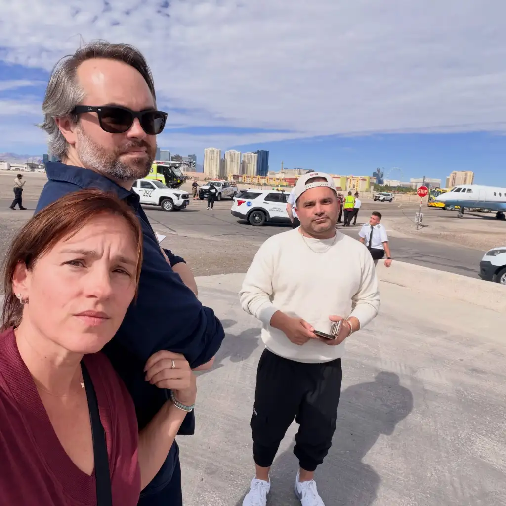 Donnie Wahlberg and two other people posing for a photo on an airport tarmac.
