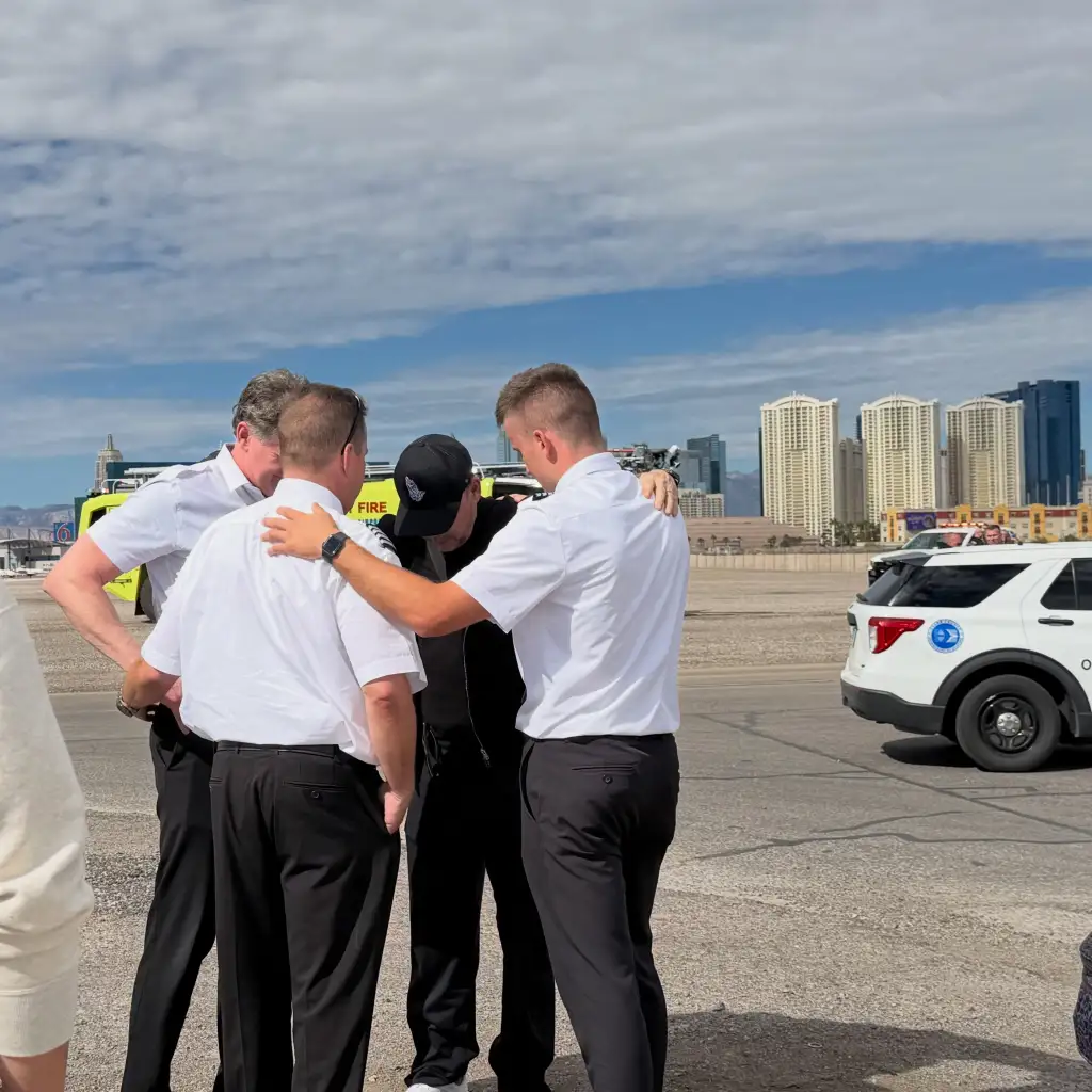 Donnie Wahlberg stands in a circle with three firefighters, with their arms around each other in prayer.