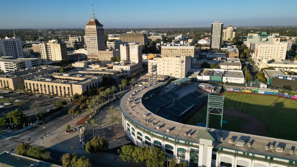 Aerial view of downtown Fresno, California, featuring Chukchansi Park baseball stadium in the foreground and the historic Bank of America building in the background.