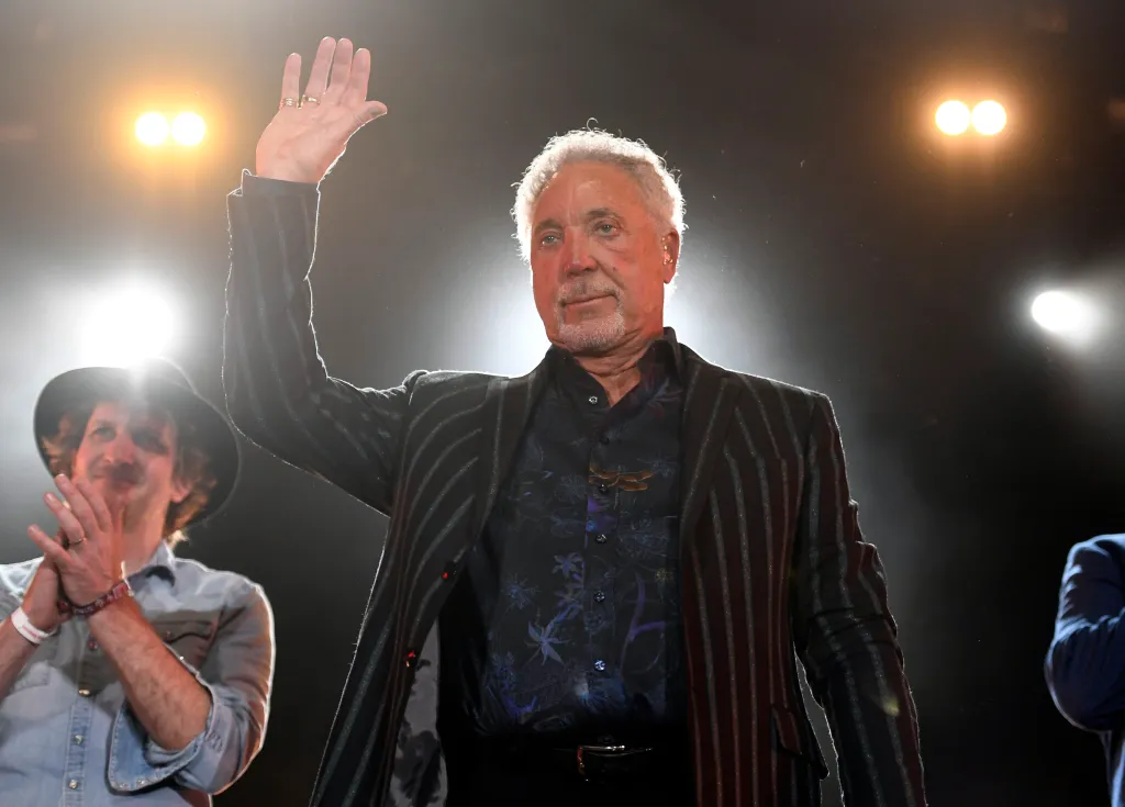 Tom Jones waves to the audience on stage.