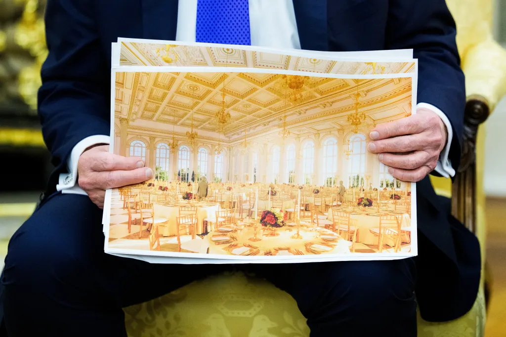 A man wearing a suit holding an architectural rendering of a ballroom.