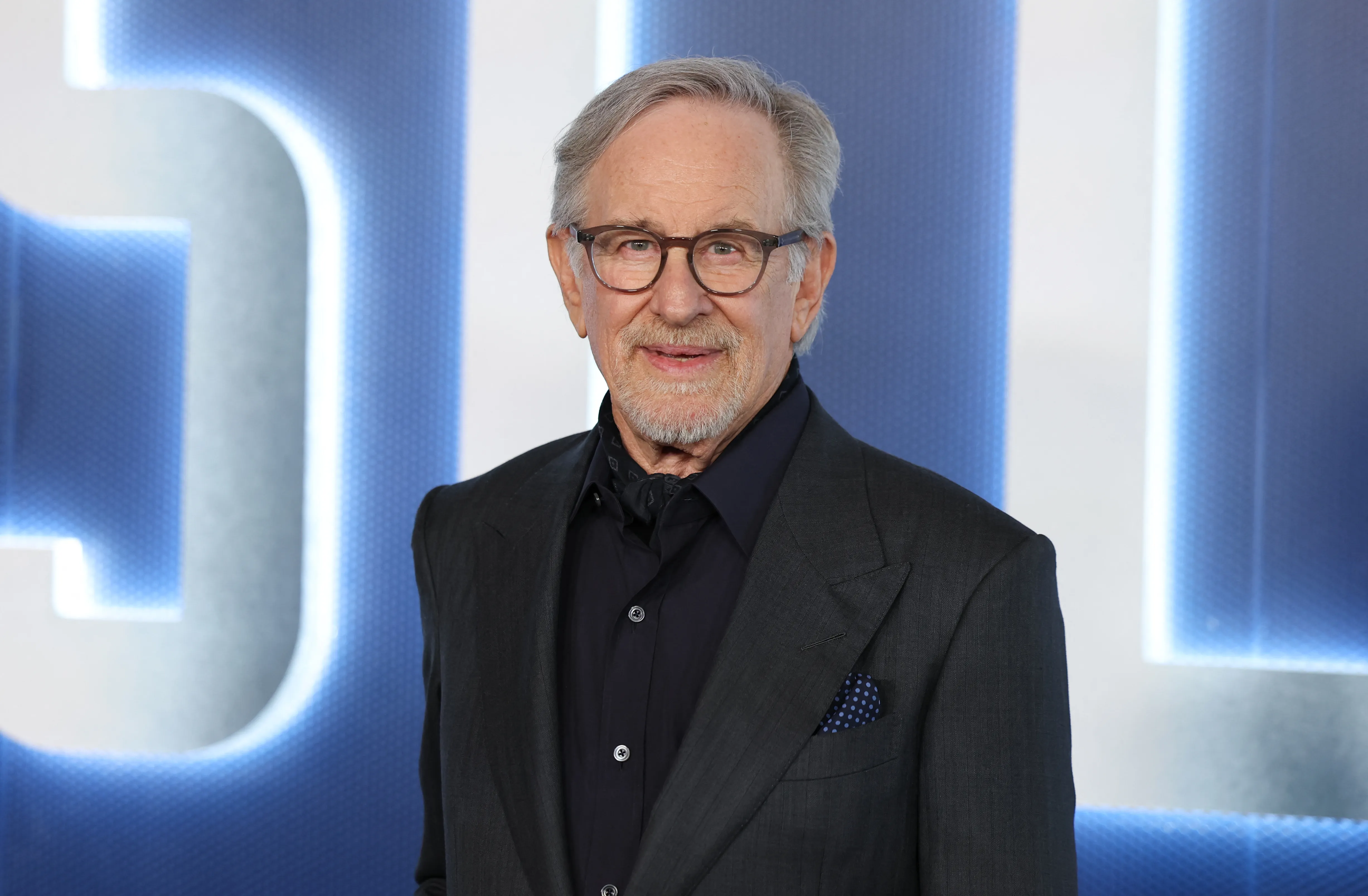 Steven Spielberg in a dark suit and glasses.