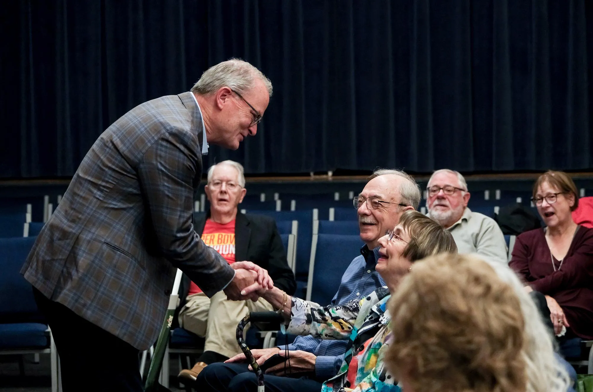 Adam Hamilton smiling and holding the hand of a woman in a small crowd of seated people Adam Hamilton smiling and holding the hand of a woman in a small crowd of seated people