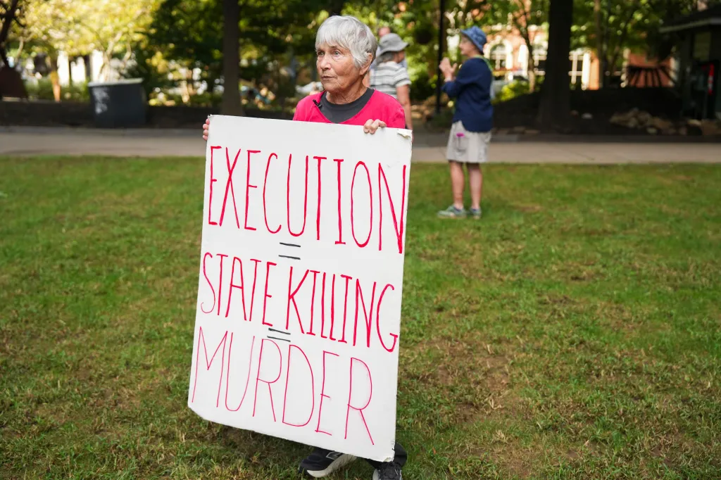 Carol Nickel holds a sign reading