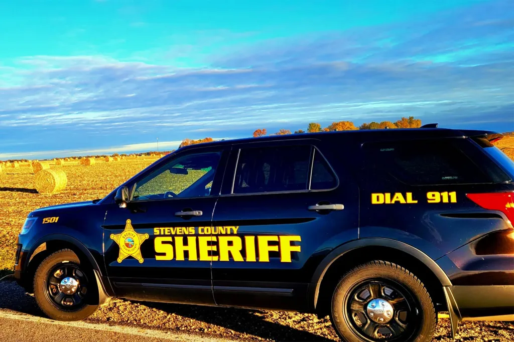 A Stevens County Sheriff's patrol vehicle parked alongside a harvested field under a blue sky.