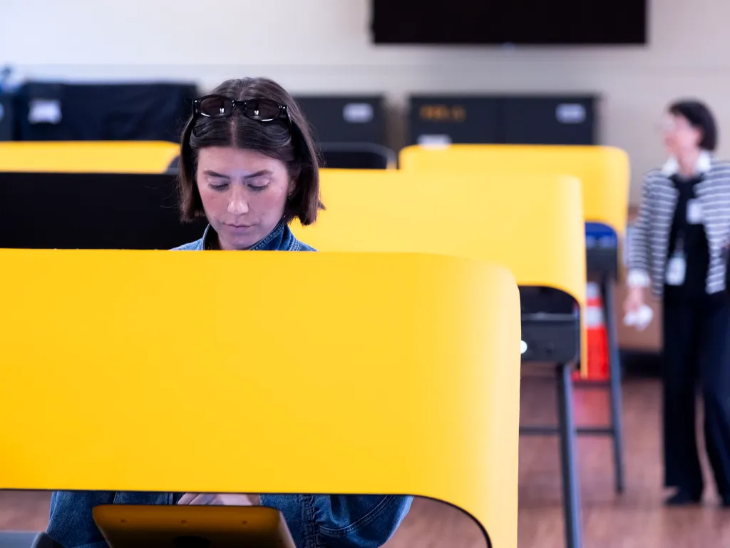 A voter fills out a ballot in a yellow voting booth in Pacific Palisades.