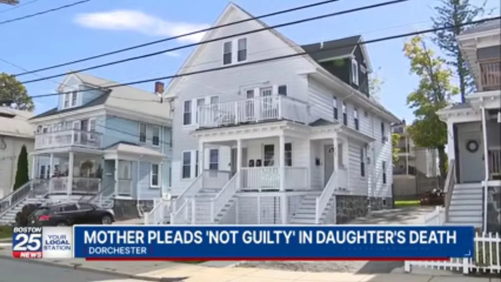 Exterior view of a multi-family white house in a residential neighborhood, with a news chyron at the bottom reading 