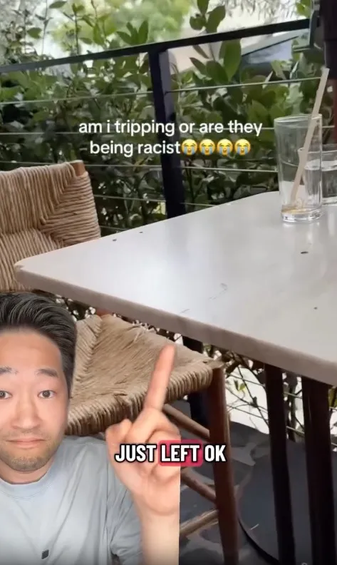 A man points his middle finger towards an outdoor restaurant table with text that says,
