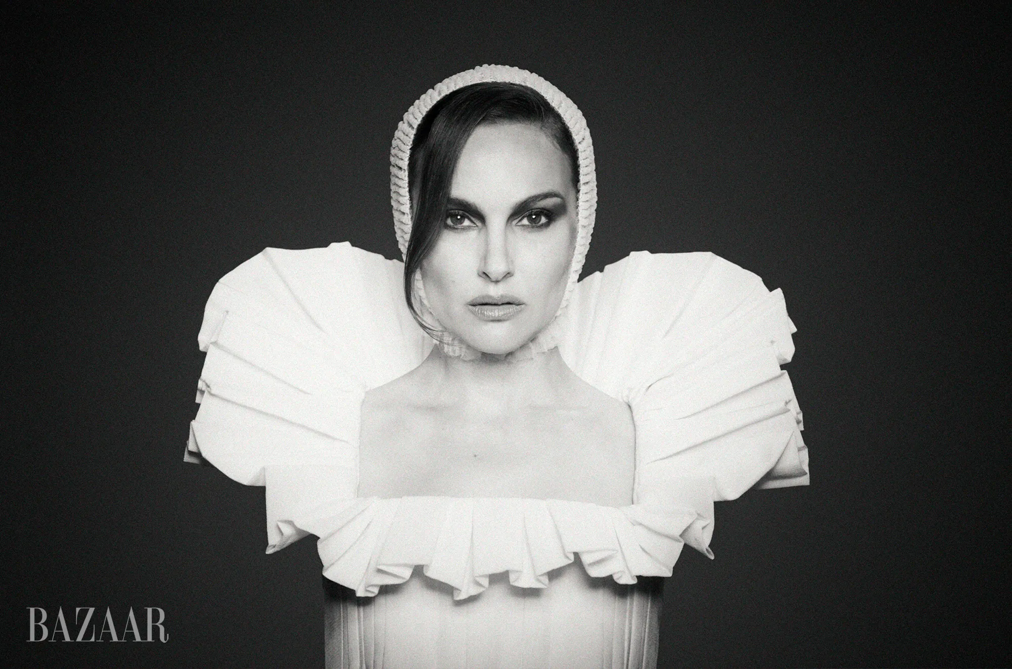 Black and white portrait of Natalie Portman wearing a ruffled collar and a knitted cap.