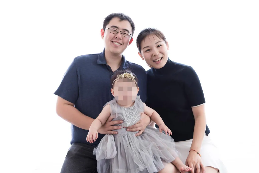 Edric Ding and Wanying Zhang, also known as Heather Zhang, pose with a baby with its face pixelated.