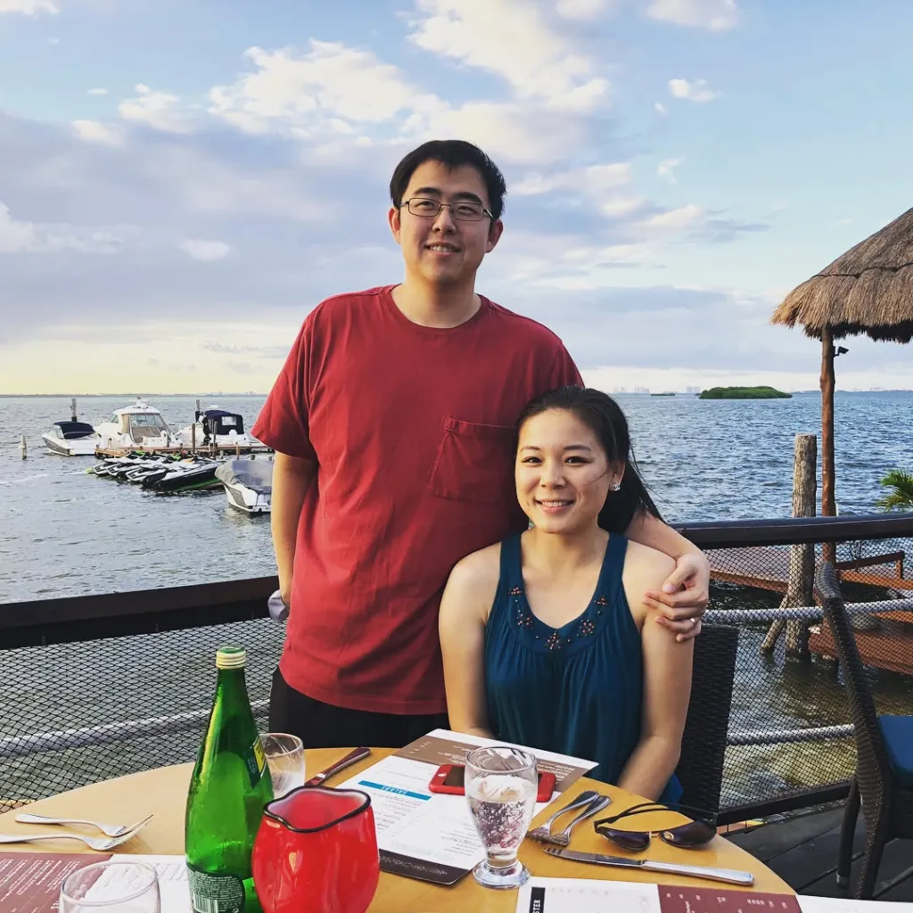 Edric Ding and Wanying Zhang pose together at a table by the water.