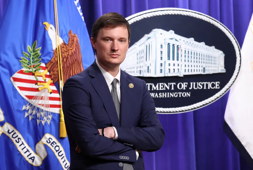 Acting US Deputy Attorney General Trent McCotter stands with his arms crossed during a press conference at the Department of Justice.