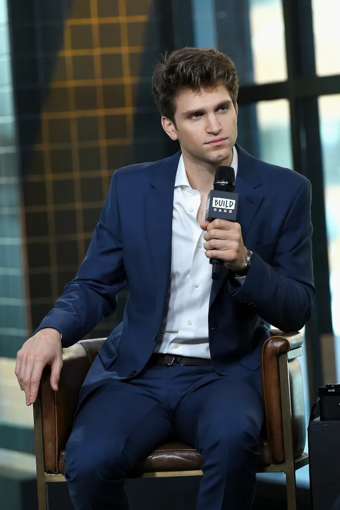 Actor Keegan Allen holds a microphone while sitting in a chair at the Build Series.