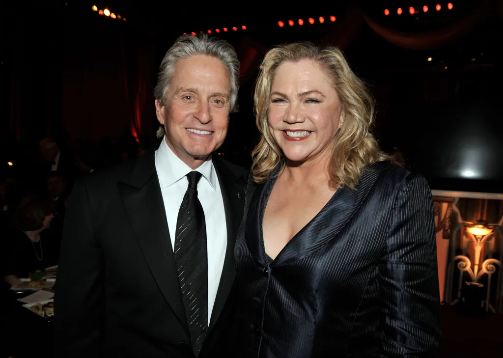 Actor Michael Douglas and actress Kathleen Turner smile together at an event.