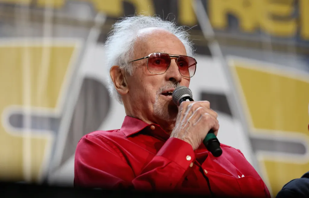Actor Michael Forest speaks into a microphone at a convention.