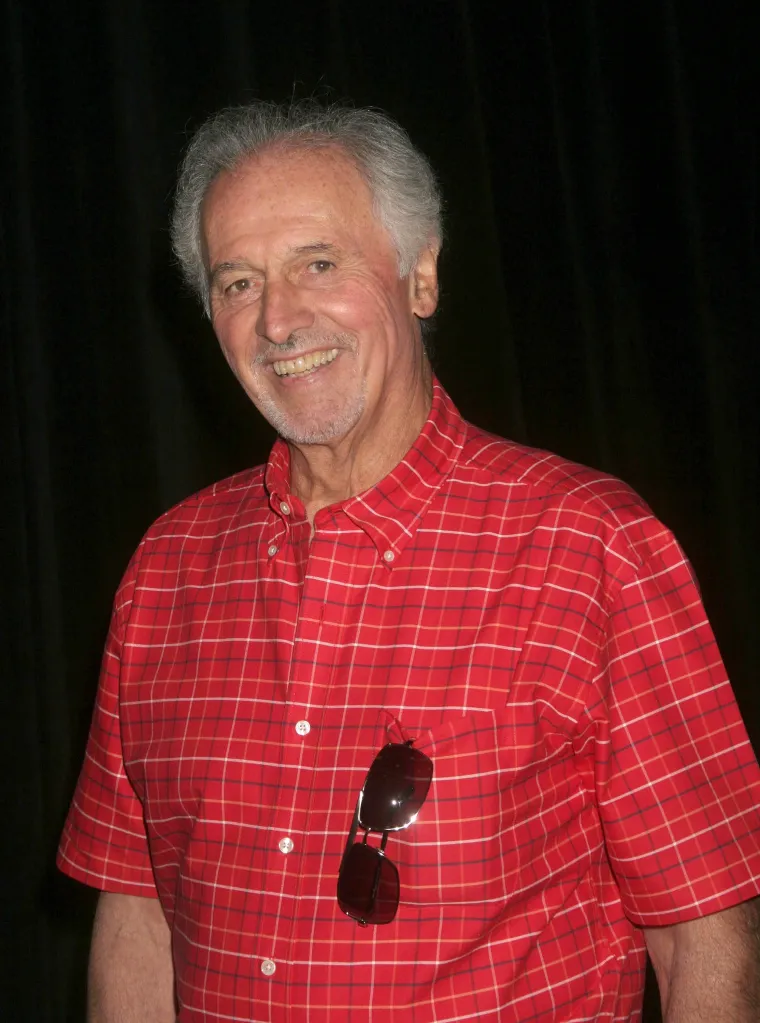Actor Michael Forest smiling and wearing a red plaid shirt.
