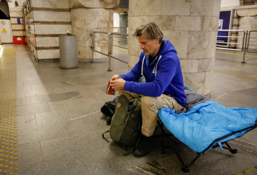 Actor Nikolaj Coster-Waldau sits on a cot inside a metro station in Kyiv.