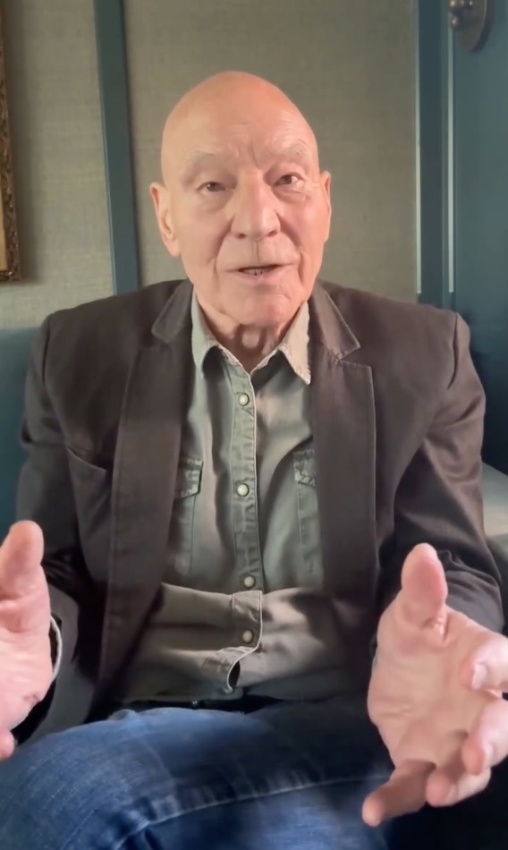 Actor Patrick Stewart speaking while gesturing with his hands.