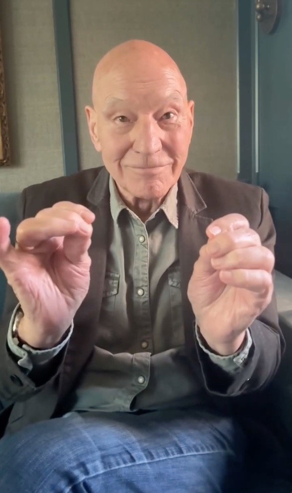 Actor Patrick Stewart smiling while gesturing with his hands.