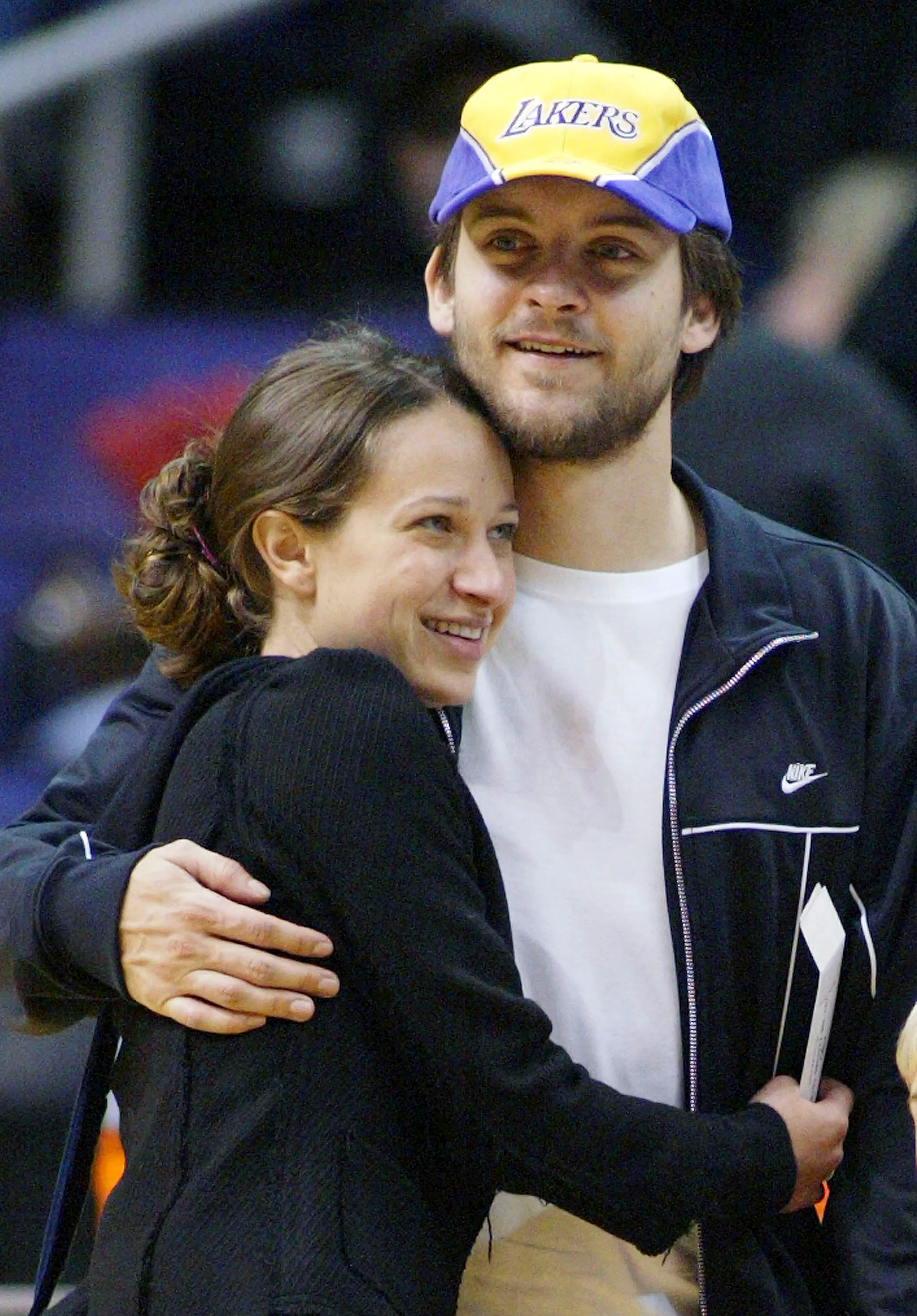 Actor Tobey Maguire and Jennifer Meyer embrace while attending a basketball game at the Staples Center.