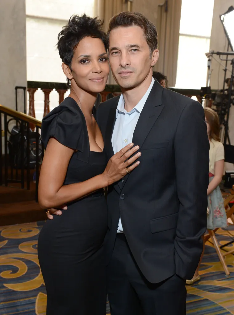 Actors Halle Berry and Olivier Martinez stand together, smiling slightly as they pose for a photo.