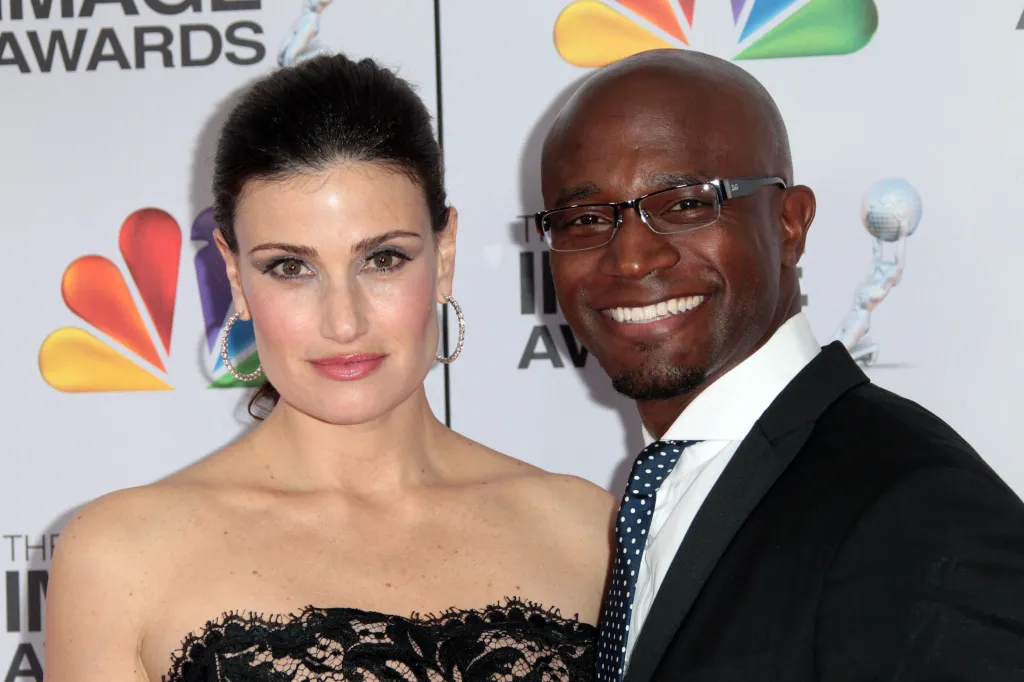 Idina Menzel and Taye Diggs pose on the red carpet at an awards event.
