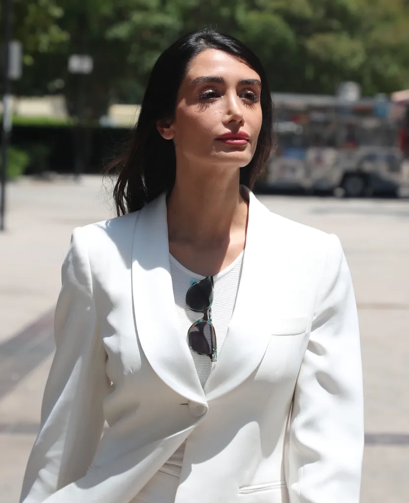 Adva Lavie exits Van Nuys Courthouse wearing a white blazer with sunglasses tucked into her shirt.