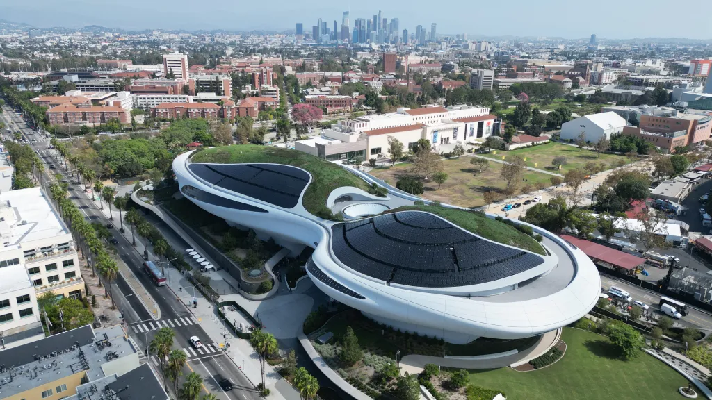 Aerial view of the Lucas Museum of Narrative Art in Los Angeles, with the city skyline in the background.
