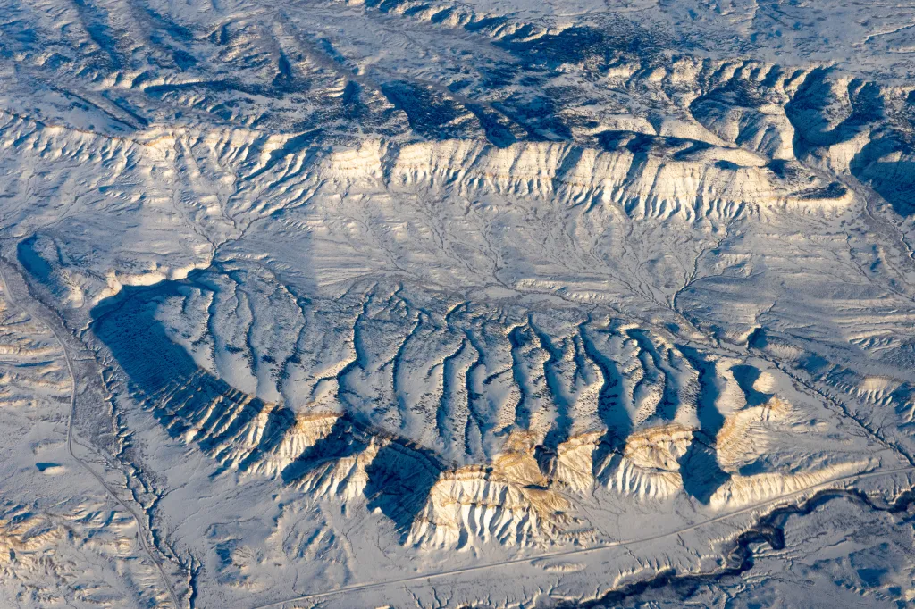 Aerial view of parallel streams on the snow-covered sloping backside of a cuesta in southern Wyoming.