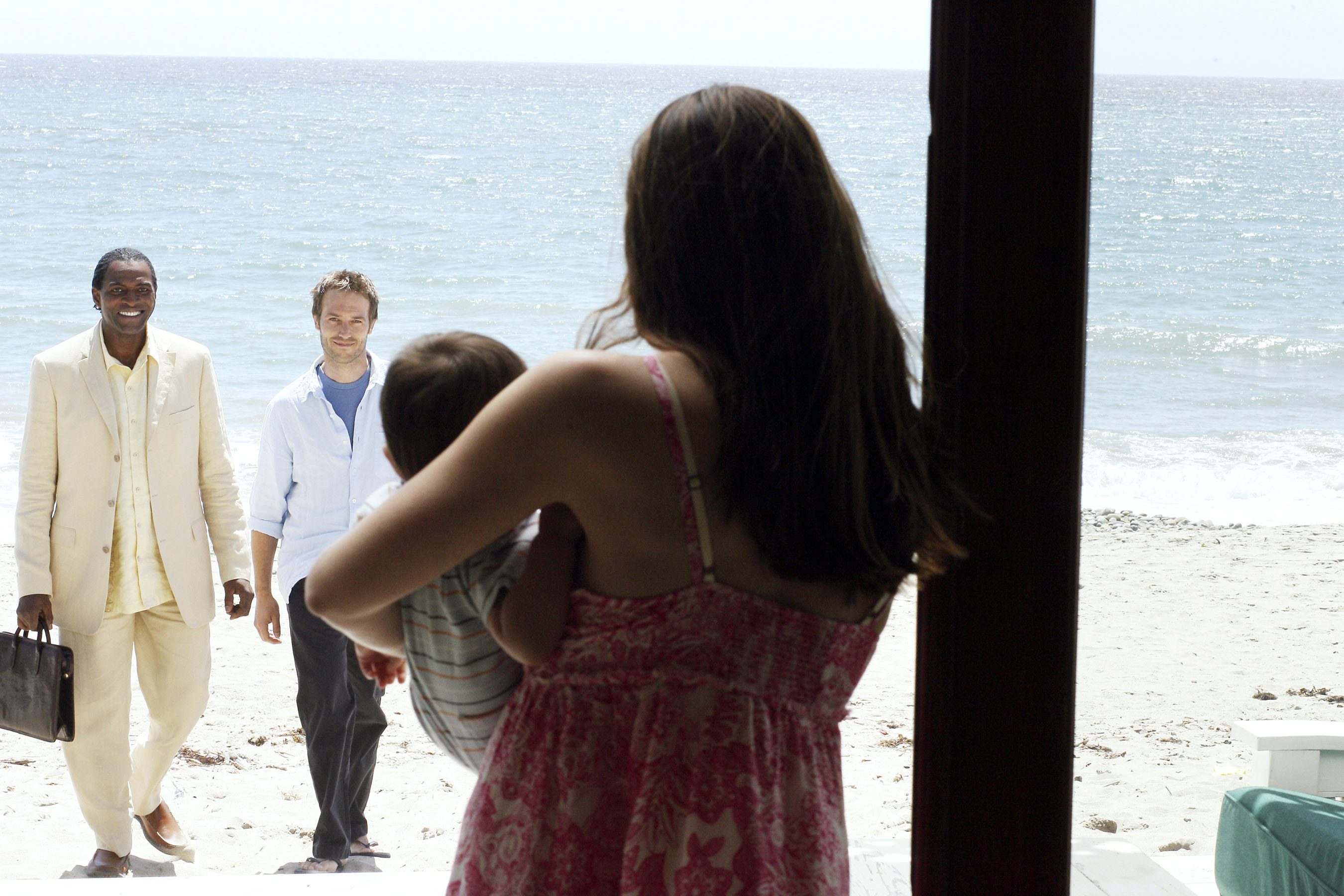 Jennifer Garner holding a child while Carl Lumbly and Michael Vartan approach on a beach.