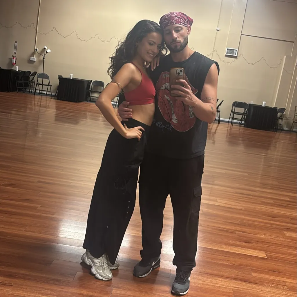 Allen Genkin and Adele Zaikman taking a mirror selfie in a dance studio.