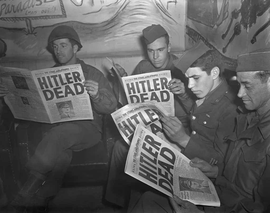 American soldiers on leave in Paris read Stars and Stripes, which features a headline announcing Hitler's death in 1945.