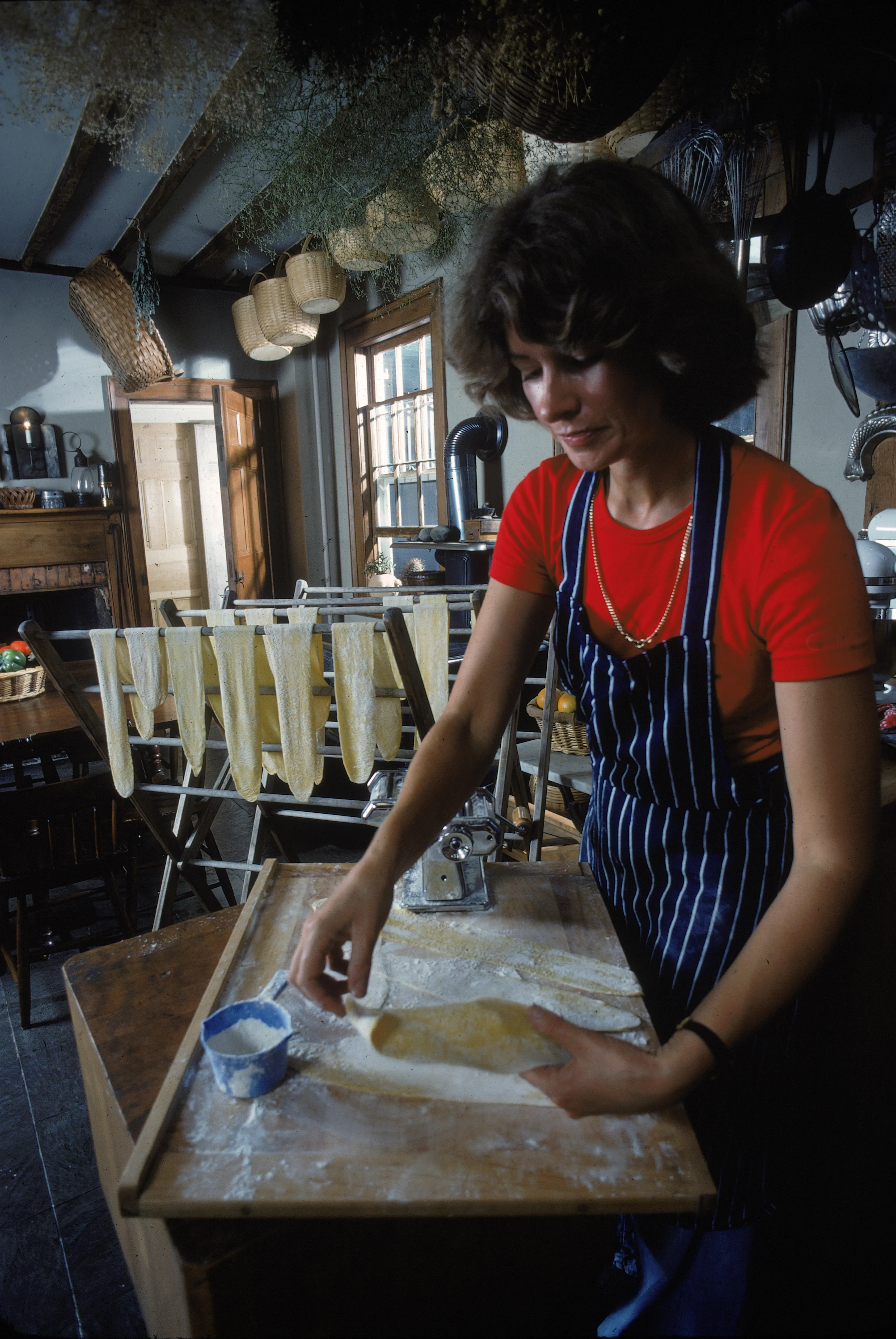 Martha Stewart folds dough on a wooden board in a rustic kitchen.