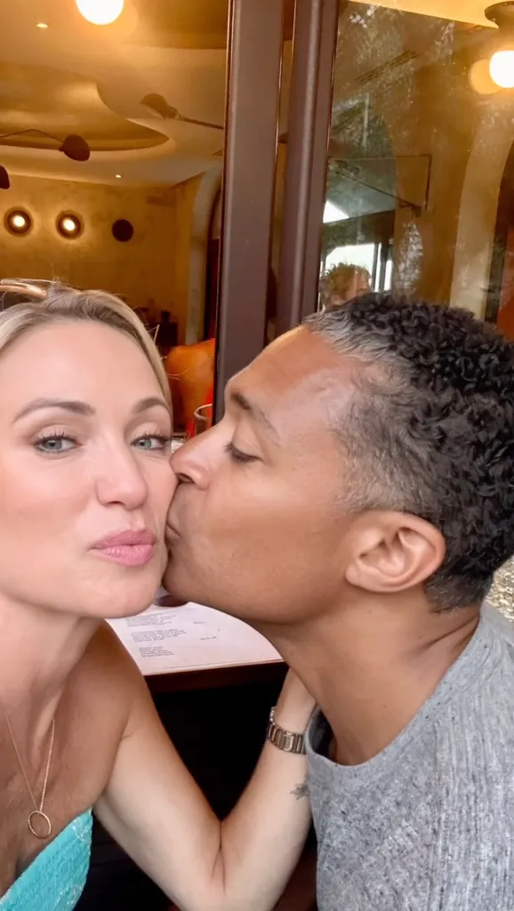 T.J. Holmes kissing Amy Robach on the cheek.
