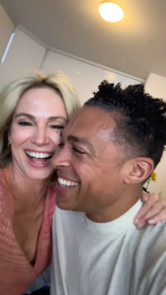 Amy Robach and T.J. Holmes smiling and laughing together indoors.