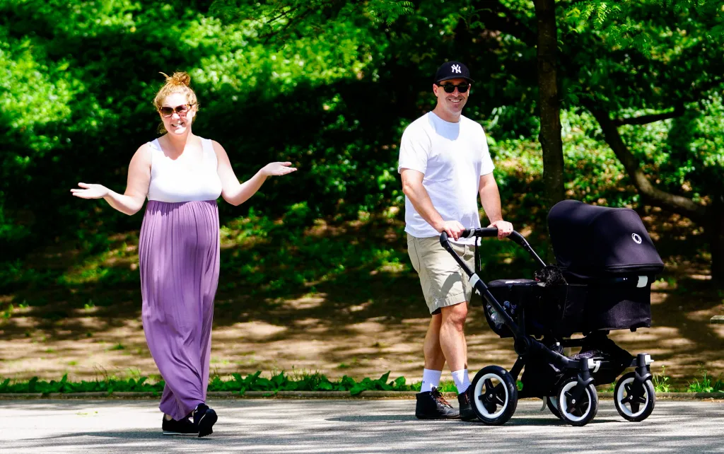 Amy Schumer and Chris Fischer in a park with baby Gene and their dog.