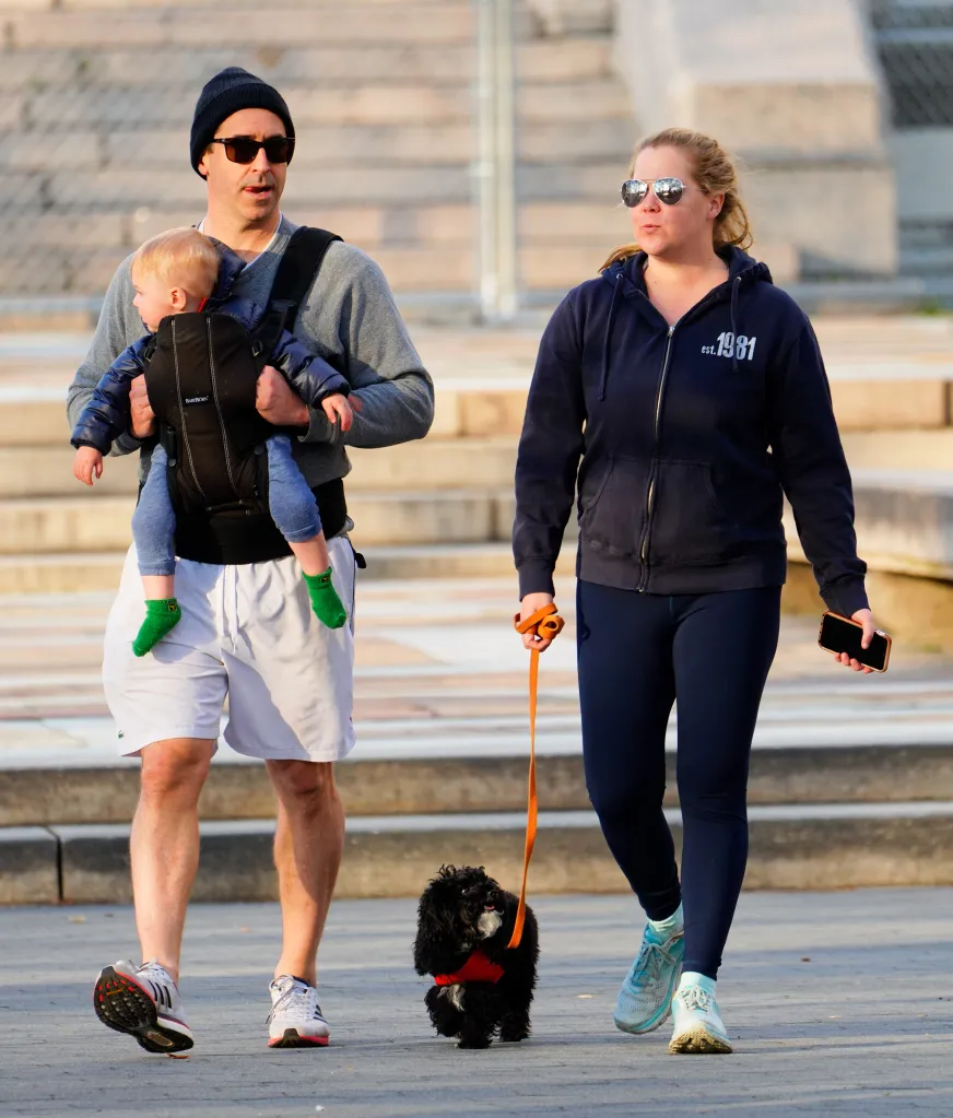 Amy Schumer and husband Chris Fischer walk with their baby and dog.