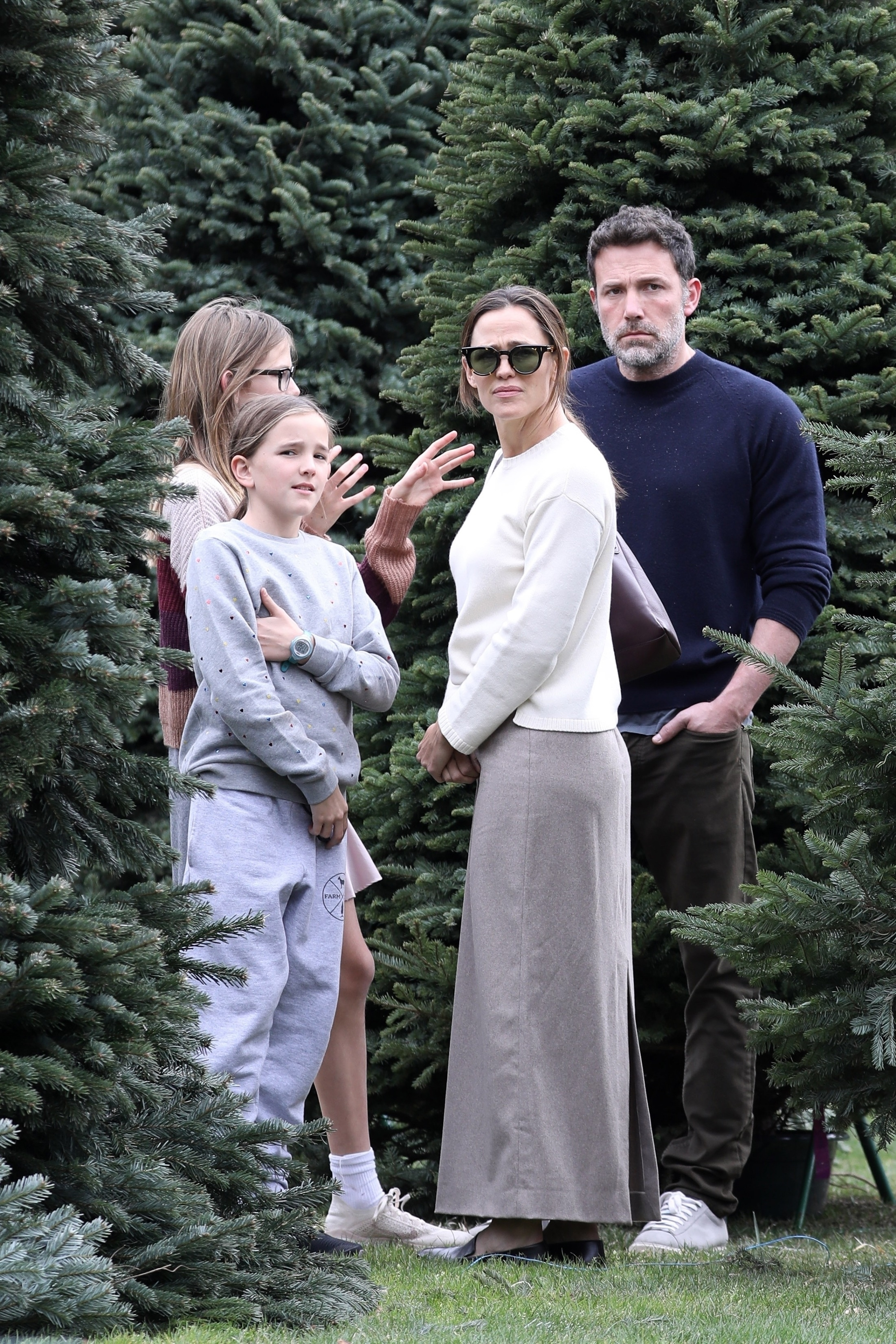 Ben Affleck and Jennifer Garner standing among Christmas trees with their children.