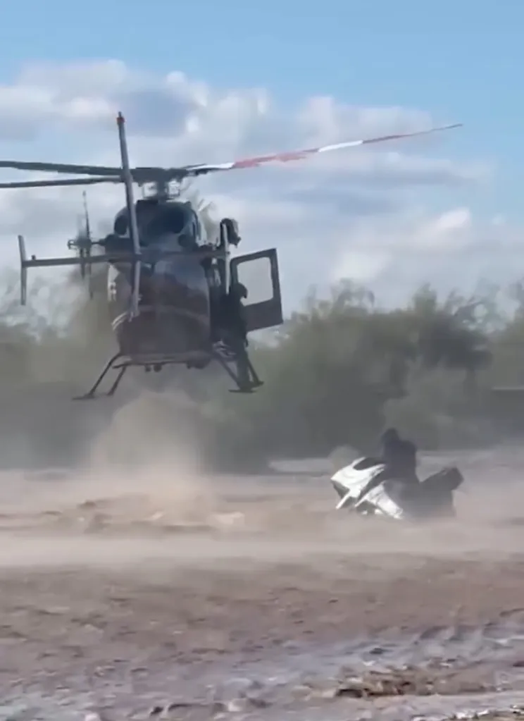 an Arizona sheriff's helicopter crew rescuing a man stranded on top of his overturned truck as rapidly moving floodwaters surrounded the vehicle.